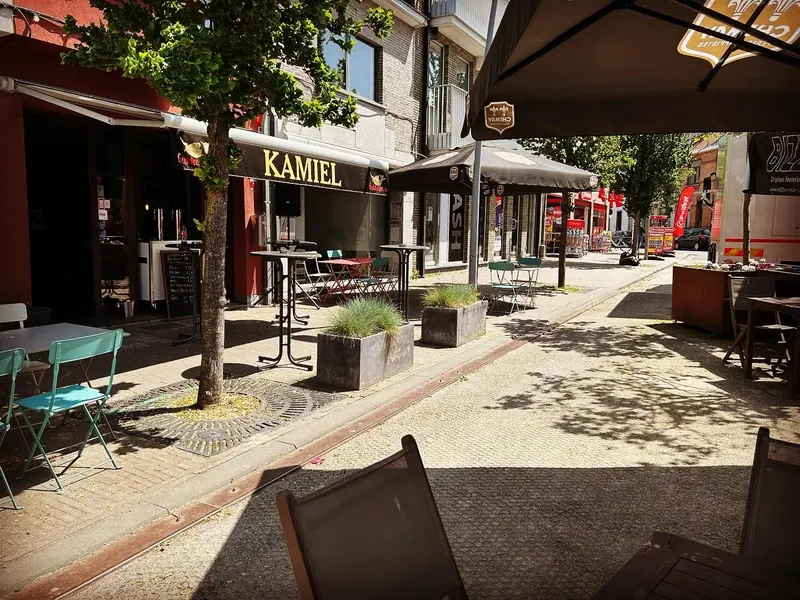 Terrastafels langs de Markt in de zon, met de rode gevel en de luifel van Kamiel links.