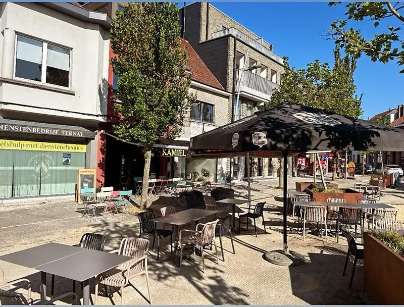 Het terras aan de Markt in de zon, met parasols, tafels en stoelen.